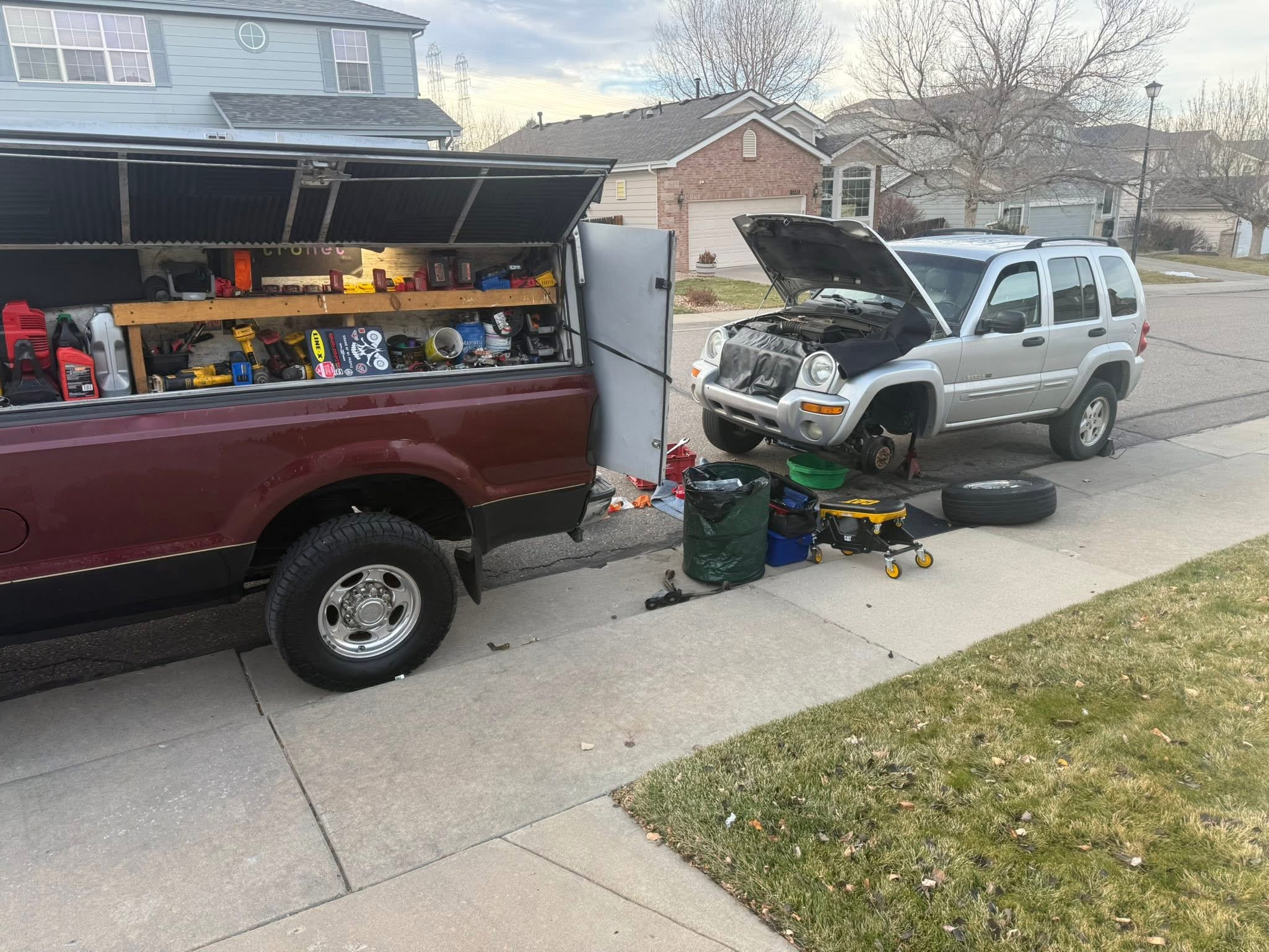 Denver Motors red mobile mechanic truck beside a vehicle repair setup
