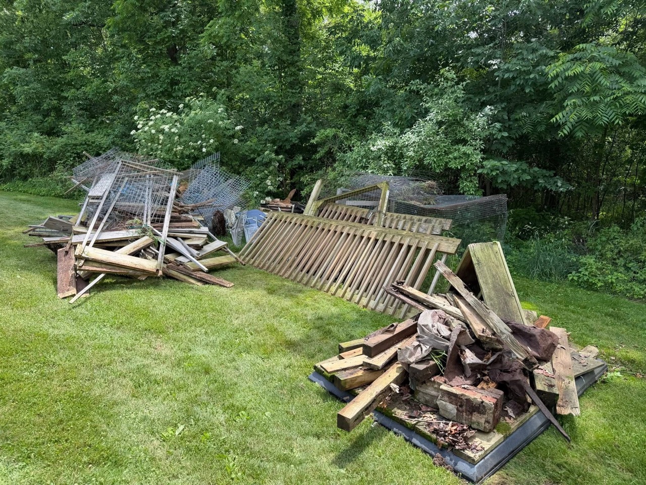 Fence boards and yard debris separated for removal