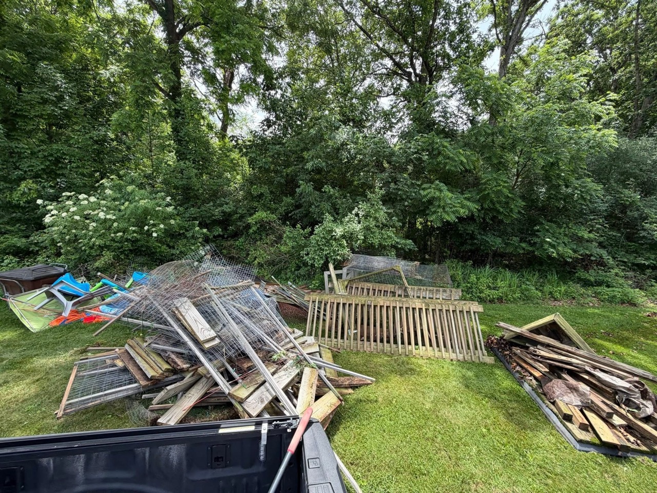 Wide yard cleanout with piles of wood and fencing debris